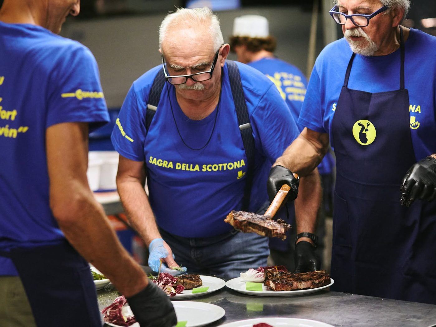 Volontari che impiattano la carne di scottona alla griglia