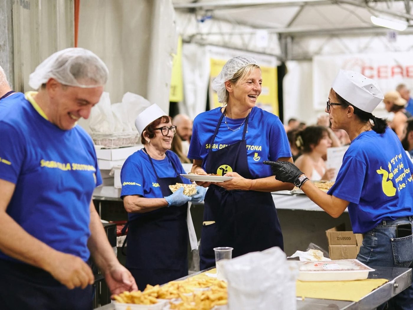Volontarie sorridenti al banco della cucina della sagra